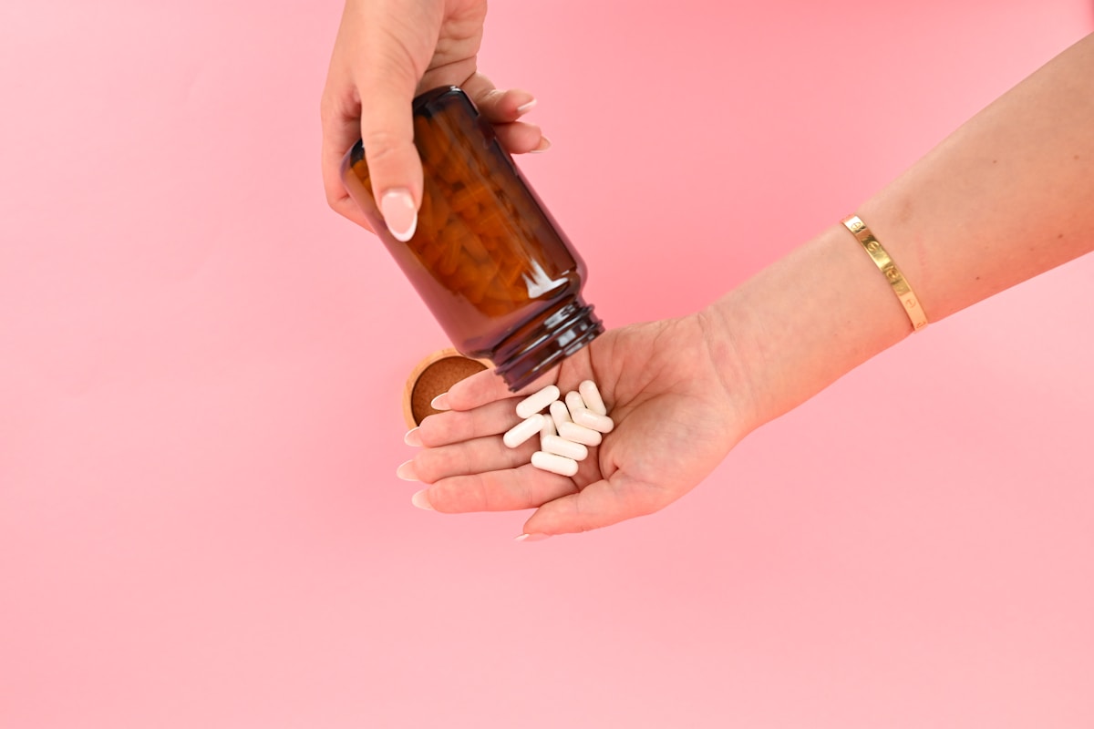 Hand pouring vitamin D softgels from a supplement bottle.